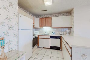 A compact kitchen with white cabinets, a microwave, a sink, and a dishwasher. - Shoreline Stepper w/ Balcony, Free WiFi, Central AC & Washer/Dryer (Ocean City)