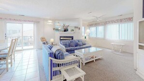 Un salon spacieux avec un canapé, une table basse et des fauteuils, un balcon avec vue et un ventilateur de plafond.