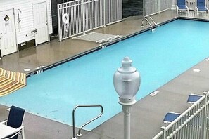 Ein Schwimmbad mit einem Rettungsring, einem Metallgeländer und einer Reihe blauer Stühle.