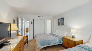 Ein Hotelzimmer mit Bett, Nachttisch, Lampe, Fernseher und Kleiderschrank.