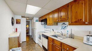 A compact kitchen with wooden cabinets, a microwave, a refrigerator, a dishwasher, and a toaster. - Old Town Ocean City condo with WiFi, washer/dryer, & pool - near boardwalk (Ocean City)