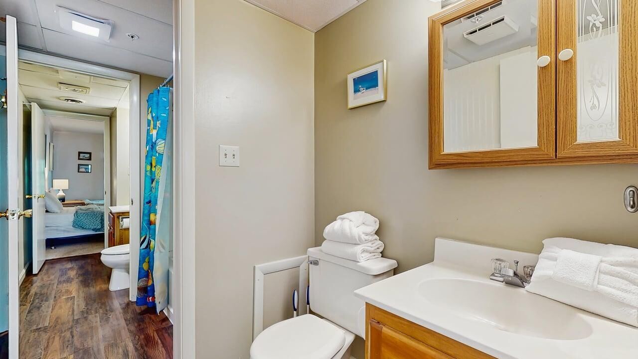 A bathroom with a toilet, sink, and mirror.