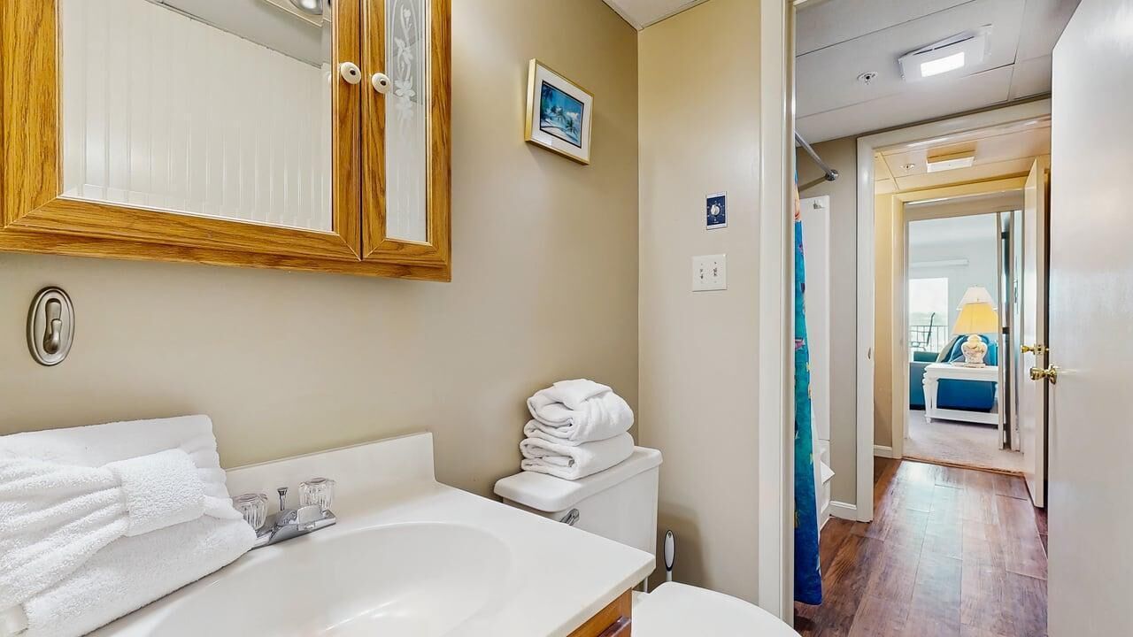 Une salle de bain équipée d’un lavabo, d’un miroir, de toilettes et de serviettes.