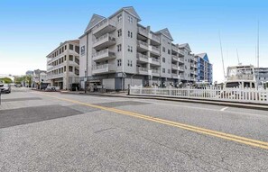 A multi-story hotel with balconies, a parking lot, and a waterfront view. - Old Town Ocean City condo with WiFi, washer/dryer, & pool - near boardwalk (Ocean City)
