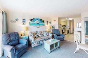 A living room with a sofa, two armchairs, a coffee table, and a dining area with a chair and table. - Oceanfront Condo with Direct Beach View, Balcony, AC, WiFi & Laundry (Ocean City)