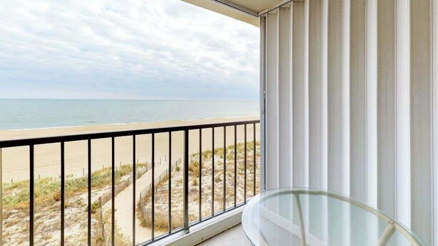 Un balcone con ringhiera in vetro che si affaccia su una spiaggia.