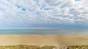 Una spiaggia con una recinzione in primo piano e un cielo nuvoloso.