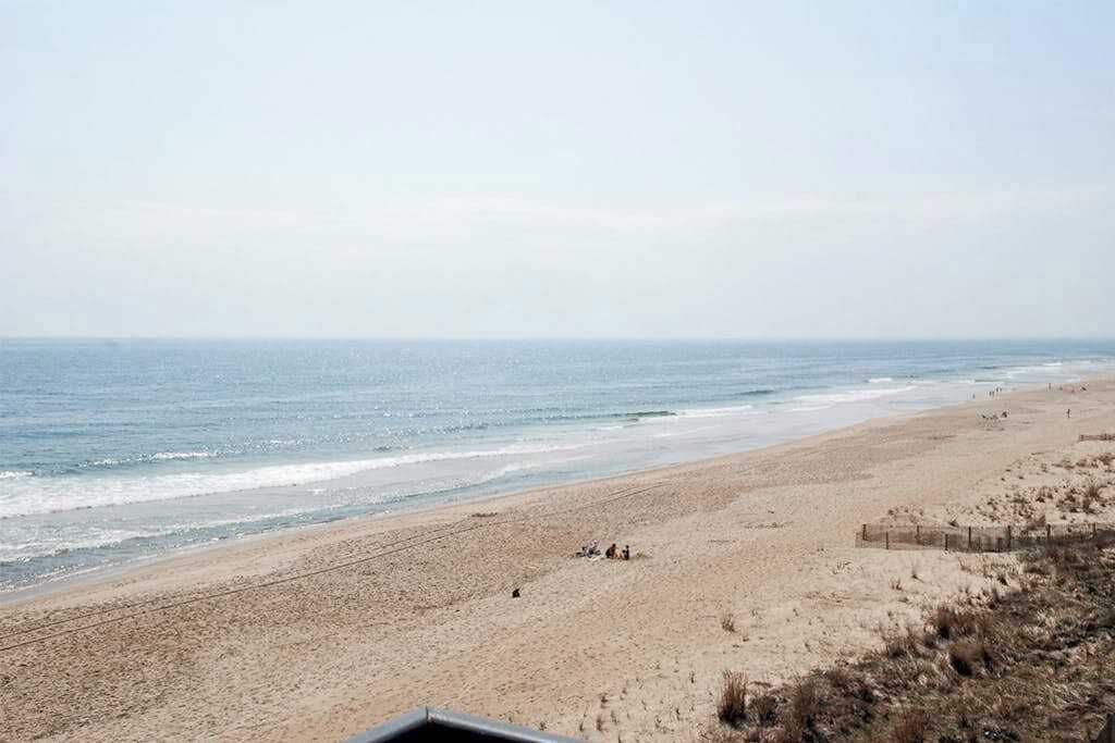 Ein Strand mit sandigem Ufer, einigen Personen und einem klaren Himmel.