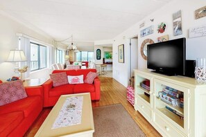 A living room with a red sofa, a television, and a cabinet with games. - Waikiki 302 (Ocean City)