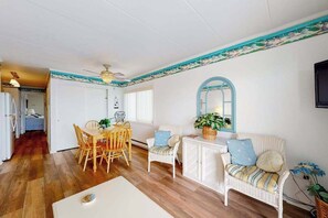 Ein Zimmer mit Esstisch, Stühlen, einer Couch, einem kleinen Schrank und einem Deckenventilator.