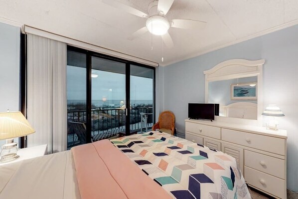 A hotel room with a large bed, a television, a dresser, and a balcony with a view. - Oceanfront Condo w/ Balcony, Great Views, NEW HVAC, W/D - Walk to Northside Park (Ocean City)