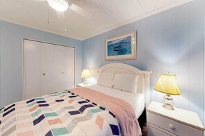A bedroom with a bed, nightstands, a lamp, a framed picture on the wall, and a door. - Oceanfront Condo w/ Balcony, Great Views, NEW HVAC, W/D - Walk to Northside Park (Ocean City)