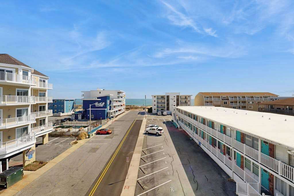 Een hotel aan de kust met meerdere verdiepingen, een parkeerplaats en uitzicht op het strand.