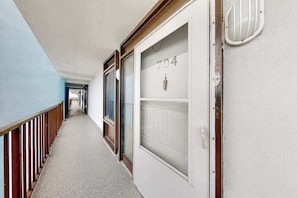 A corridor with a door labeled '704' and a window with frosted glass. - 7th-floor condo with sunset & ocean views, pool, balcony, outdoor shower, W/D (Ocean City)