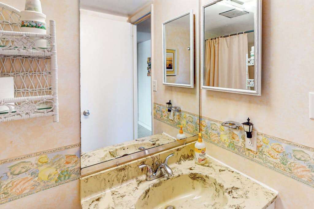 Une salle de bain avec un grand miroir, un lavabo et un rideau de douche.