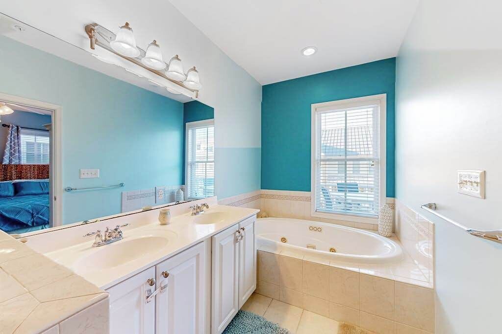 Un bagno con doppio lavabo, una vasca e un grande specchio.