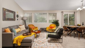 Ein Wohnzimmer mit einer Couch, Sesseln, einem Couchtisch und einem Essbereich mit Tisch und Stühlen.