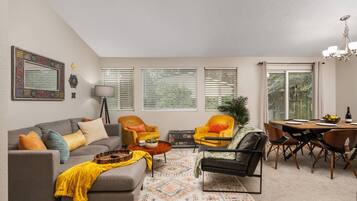 A living room with a sofa, armchairs, a coffee table, and a dining area with a table and chairs.