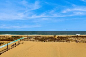 Ein Strand mit einem Zaun, einer Bank und blauem Himmel.