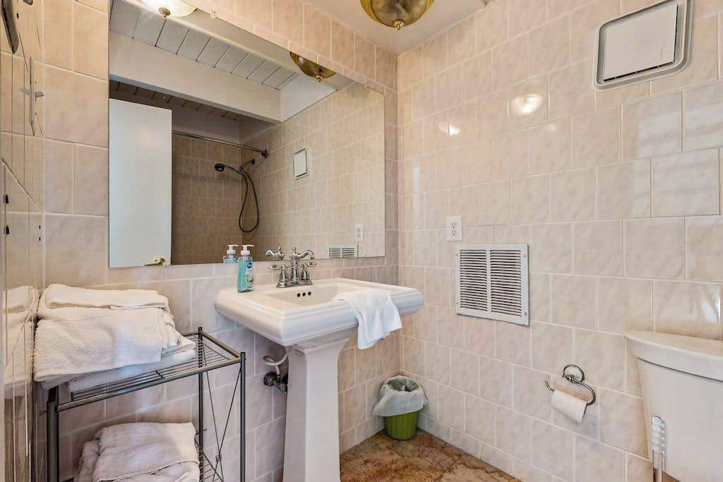 A bathroom with a sink, mirror, towel rack, shower, and toilet.