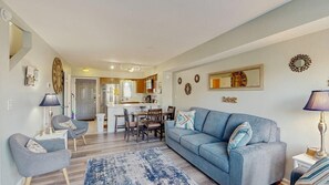 A living room with a sofa, chairs, a coffee table, and a rug. There is a kitchen area with a dining table and chairs. - Attractive & Convenient Vacation Home w/Private Washer/Dryer, Central AC, WiFi (Ocean City)