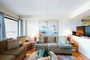 A living room with a sofa, a coffee table with a plant, two lamps, and a painting on the wall. - High Point South P1 (Ocean City)