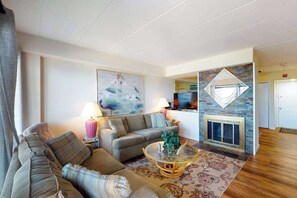 A living room with a sofa, a coffee table, a fireplace, and a painting on the wall. - High Point South P1 (Ocean City)