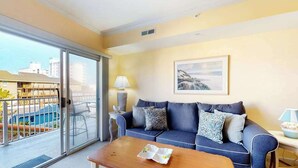 A living room with a sofa, a coffee table, a lamp, and a painting on the wall. - Family-Friendly Condo near the Beach w/Fireplace, W/D, Shared Outdoor Pool, A/C (Ocean City)
