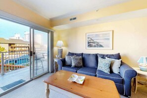 A living room with a sofa, a coffee table, a lamp, and a painting on the wall. - Family-Friendly Condo near the Beach w/Fireplace, W/D, Shared Outdoor Pool, A/C (Ocean City)