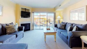 A living room with a fireplace, two sofas, a coffee table, and a TV. - Family-Friendly Condo near the Beach w/Fireplace, W/D, Shared Outdoor Pool, A/C (Ocean City)