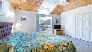 Ein Schlafzimmer mit einem Bett, einem Fernseher, einem Deckenventilator und einer Tür, die zu einem Außenbereich führt.