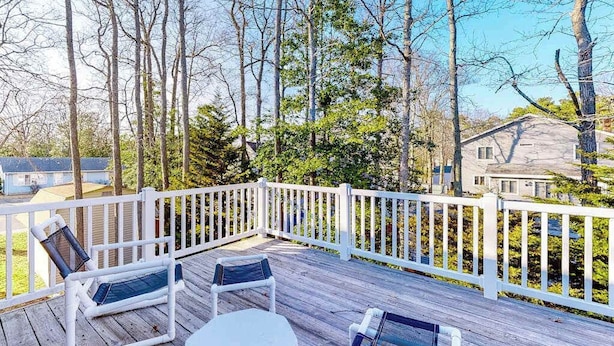 Eine Holzterrasse mit weißen Geländern, zwei Stühlen und einem Tisch.