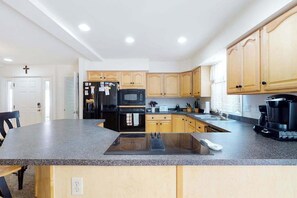 A modern kitchen with granite countertops, a built-in oven, a microwave, and wooden cabinets. - Large, Quiet Family Home w/ Deck, Porch & WiFi - Walk to the Beach, Shops & More (Ocean City)