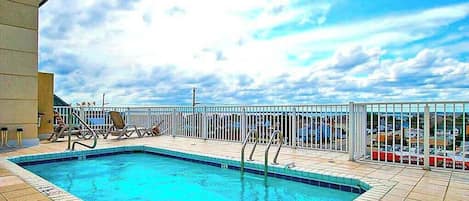 Une piscine entourée d’une clôture blanche, un ciel dégagé et une vue sur la mer.
