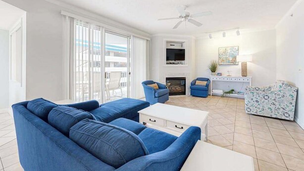 A living room with a blue sofa, a white coffee table, and a fireplace. - Family-Friendly Beach Condo: Balcony, w/d, shared outdoor pool & gym (Ocean City)