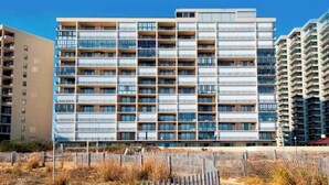 En flervåningsbostadsbyggnad med modern design, utrustad med balkonger och stora fönster.