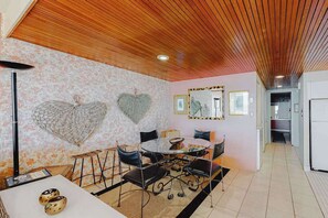 A dining area with a round table, chairs, and a ceiling with wooden slats. - Oceanfront condo with pool, AC, balcony, & washer/dryer (Ocean City)