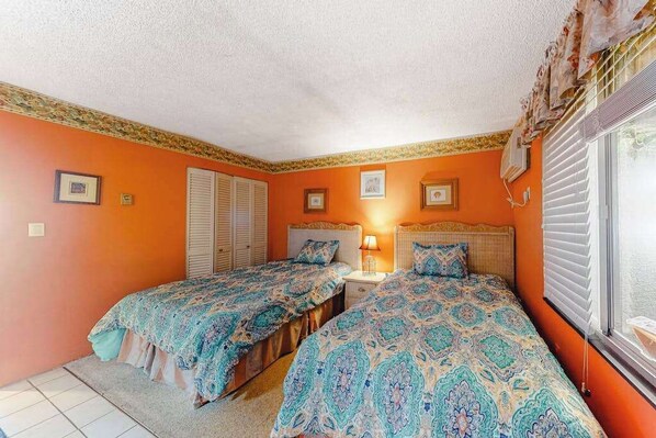 A bedroom with two beds, a nightstand, and a window with blinds. - Oceanfront condo with pool, AC, balcony, & washer/dryer (Ocean City)