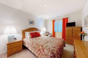 A bedroom with a bed, bedside tables, a TV, a wardrobe, and a window with curtains. - Wonderful bayfront condo overlooking the marina with pool, balcony & fireplace (Ocean City)