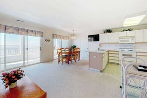 A modern apartment with a dining area, kitchen, and large windows. - Wonderful bayfront condo overlooking the marina with pool, balcony & fireplace (Ocean City)
