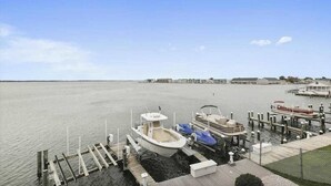 Ein Yachthafen mit vertäuten Booten, eine Pier, die ins ruhige Wasser führt, und Gebäude im Hintergrund.