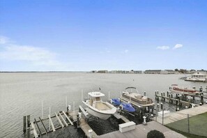 A marina with boats docked, a pier extending into calm water, and buildings in the background. - Wonderful bayfront condo overlooking the marina with pool, balcony & fireplace (Ocean City)