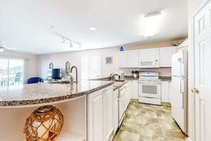 A kitchen with white cabinets, a granite countertop, a stove, and a microwave. - Waterfront Condo on the Canal w/ Deck & Shared Pools/Tennis - Walk to the Beach (Ocean City)