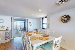 A dining area with a white table and chairs, a starfish decoration, and a view through an open door. - Irene 607 (Ocean City)