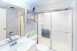 Ein modernes Badezimmer mit Duschkabine aus Glas, einem weißen Waschbecken und einem Spiegel.