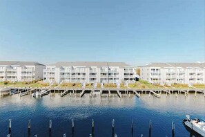 A row of modern, multi-story buildings with balconies, docked boats, and a calm water body in the foreground. - Chic condo with pool, patio, central AC & washer/dryer - blocks to the beach (Ocean City)