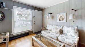 Ett vardagsrum med en soffa, ett soffbord, en vägglampa och en inramad tavla.