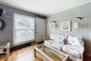 A living room with a sofa, a coffee table, a wall-mounted lamp, and a framed picture. - Gullway Getaway (Ocean City)