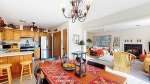 Cocina moderna con armarios de madera, una isla central y un comedor con mantel estampado.