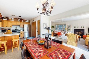 A modern kitchen with wooden cabinets, a central island, and a dining area with a patterned tablecloth. - Canal-front home with boat dock, large deck, AC, washer/dryer & WiFi (Ocean City)
